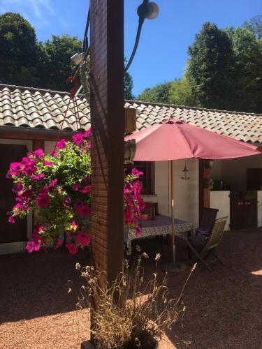 a house with a pink umbrella and some flowers at My little sweet home in Colombe