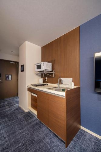 a kitchen with a sink and a microwave at GRAND BASE Okayama Ekimae in Okayama