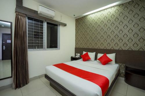 a bedroom with a bed with red pillows and a window at Hotel Grand Kartika in Samarinda