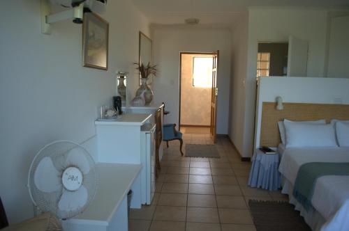 a bedroom with a bed and a desk and a sink at Crowned Crane in Gonubie