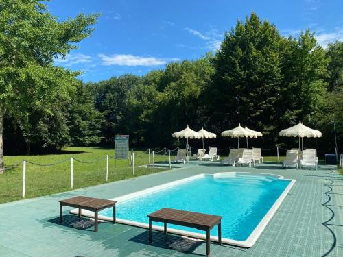einen Pool mit 2 Tischen, Stühlen und Sonnenschirmen in der Unterkunft Park Hotel Junior in Quarto dʼAltino