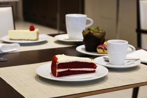 a table with a slice of cake and cups of coffee at Hyatt House Jeddah Sari Street in Jeddah