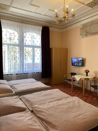 a bedroom with two beds and a table and a tv at Hotel Gunia in Berlin