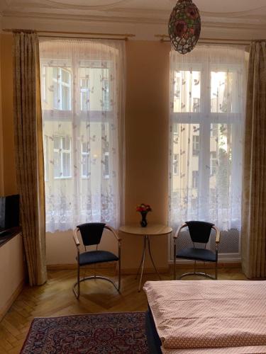 a bedroom with two chairs and a table and two windows at Hotel Gunia in Berlin