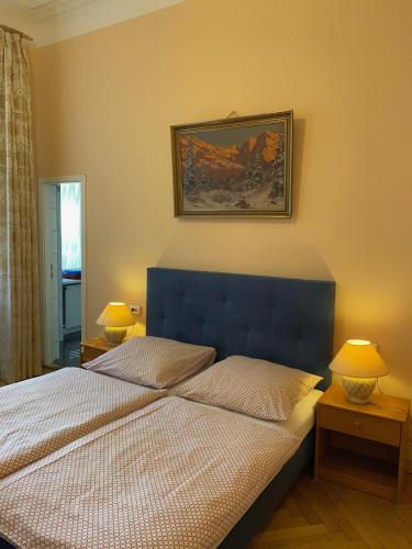 a bedroom with a bed with a blue headboard and two lamps at Hotel Gunia in Berlin