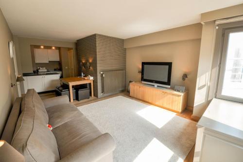 a living room with a couch and a flat screen tv at Beverly house in Knokke-Heist