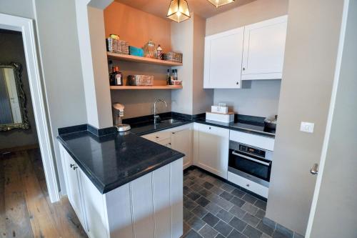 eine Küche mit weißen Schränken und einer schwarzen Arbeitsplatte in der Unterkunft Beverly house in Knokke-Heist