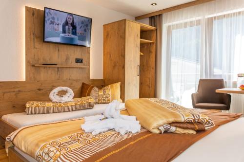 a bedroom with two beds with a television on the wall at Garni Samnaun in Kappl