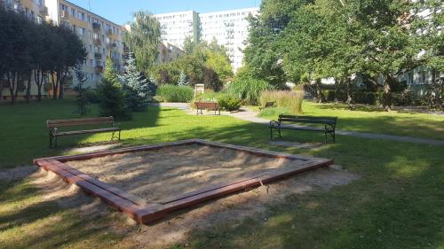 a park with two benches and a trampoline in the grass at Stara Piekarnia - Apartament Dworcowa in Olsztyn