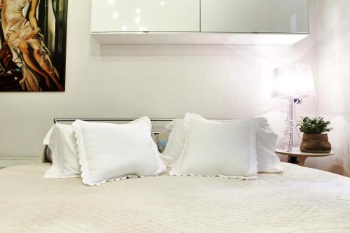 a white bed with white pillows and a painting at Petite Suite in Bergamo
