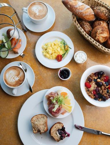 a table with plates of food and cups of coffee at Karl August - a Neighborhood Hotel in Nürnberg