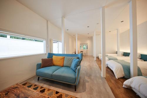 a bedroom with a blue chair and two beds at ADAN RESORT 縁 - En - in Motobu