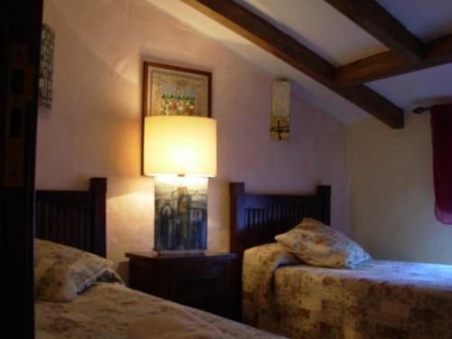 1 dormitorio con 2 camas y una lámpara en la pared en La Tiná, en Segura de la Sierra
