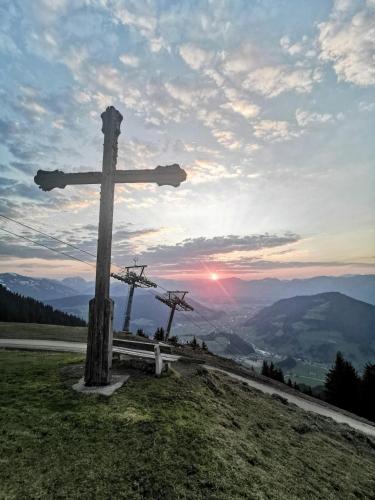 a wooden cross on top of a hill with the sunset at KRAFTalm in Itter