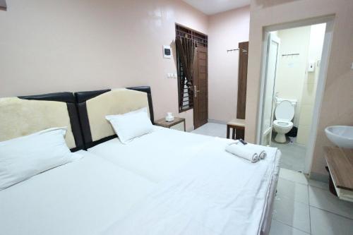 um quarto com uma grande cama branca e um lavatório em O2 Residence em Medan