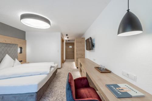 a bedroom with a bed and a desk and a chair at Hotel Grauer Bär in Sölden