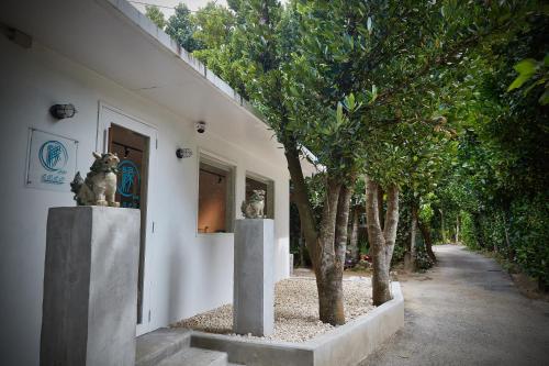 a building with two statues next to a hallway with trees at ADAN RESORT 縁 - En - in Motobu