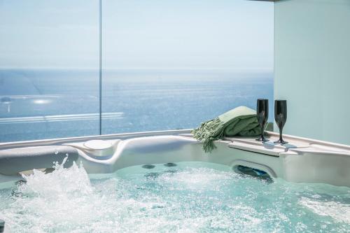 une baignoire remplie d'eau à côté d'une fenêtre dans l'établissement Oikos Boutique Residences Private Estate, à Plateies