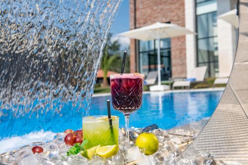 a table with two drinks and fruit next to a fountain at Villa Mosavali in Akhalubani