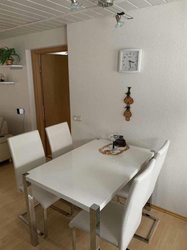 a white dining room table with white chairs and a clock at Ferien in Altenberg in Kurort Altenberg