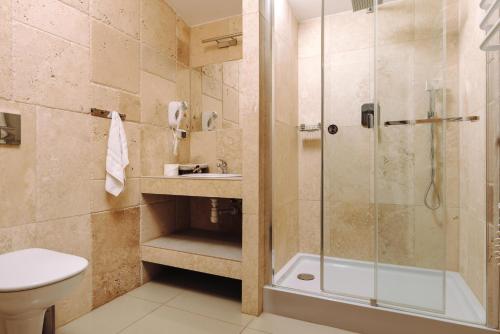 a bathroom with a shower and a toilet and a sink at Hotel Legenda in Toruń