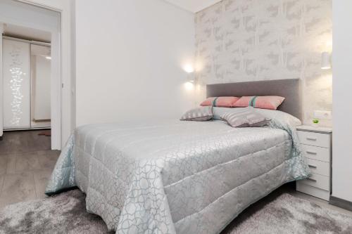Habitación blanca con cama con almohadas rosas en Espanatour VERONICA, en Torrevieja