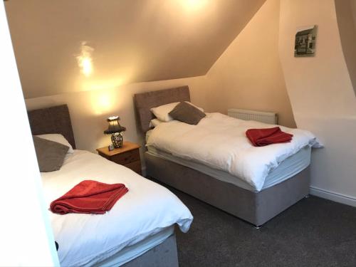 - 2 lits dans une chambre avec 2 serviettes rouges dans l'établissement Bottesford Cottage - Leicestershire, à Bottesford