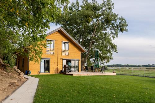 a yellow house on a lawn with a field at Houses with a View#Sauna#Jaccuzi in Gozdowice