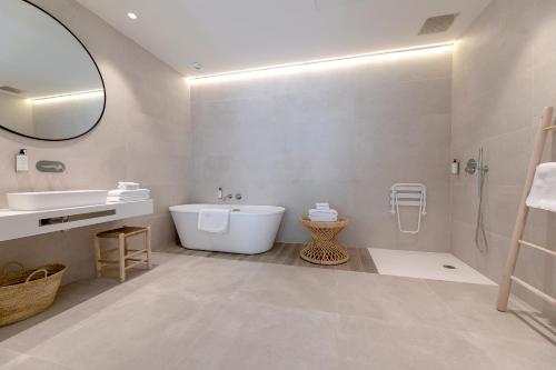 a bathroom with a tub and a sink and a mirror at Les Suites de Collioure in Collioure