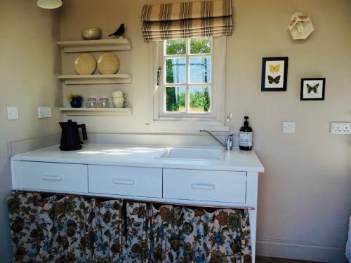 a kitchen with a white sink and a window at The Oaks Glamping - Rubie's Shepherds Hut in Colkirk