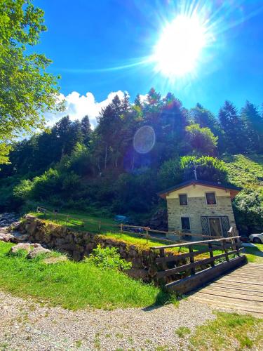 a building on a hill with the sun in the sky at ALLA STALLA Suite & Chalet in Piazzatorre