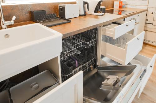 an open dishwasher in a kitchen with a sink at Lapmanni Holiday Home in Haapsalu