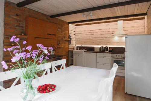 a kitchen with a white table with flowers in a vase at Lapmanni Holiday Home in Haapsalu