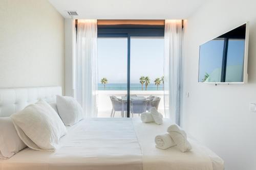 1 dormitorio con cama blanca y vistas al océano en ApartUP Denia Beachfront Deluxe, en Denia