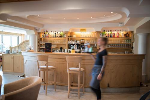 a woman is standing in front of a bar at Hotel Eichenhof in Tirolo