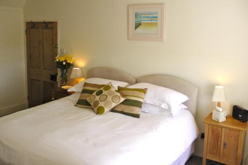a bedroom with a white bed with pillows at Lellizzick Farmhouse in Padstow