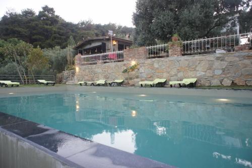 a swimming pool with a stone wall and a house at Kirkinca Hotel in Selçuk