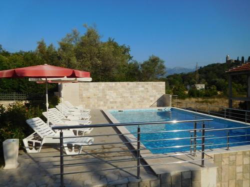a pool with chairs and a table and an umbrella at Apartments Sunrise in Tivat