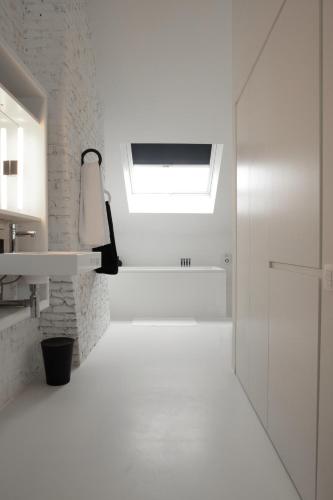 a white bathroom with a skylight and a window at Maison Nationale City Flats & Suites in Antwerp