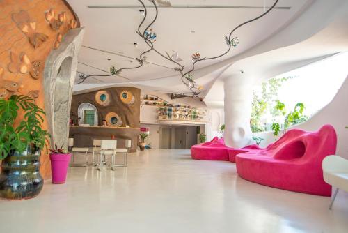a room with pink chairs and a wall with plants at Bougainville Bay Hotel in Sarandë