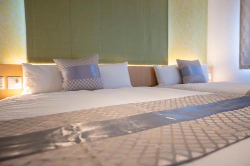 a large bed with pillows on top of it at GRAND BASE Okayama Ekimae in Okayama