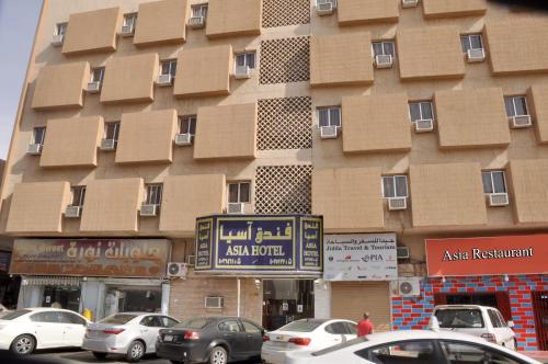 un edificio alto con coches estacionados frente a él en Asia Hotel, en Riad