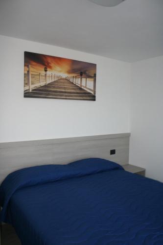 a bedroom with a blue bed with a picture on the wall at appartamenti i fiori del lago in Laveno-Mombello