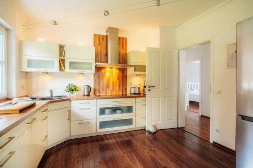 a kitchen with white cabinets and a wooden floor at FeWoLa in Wieda