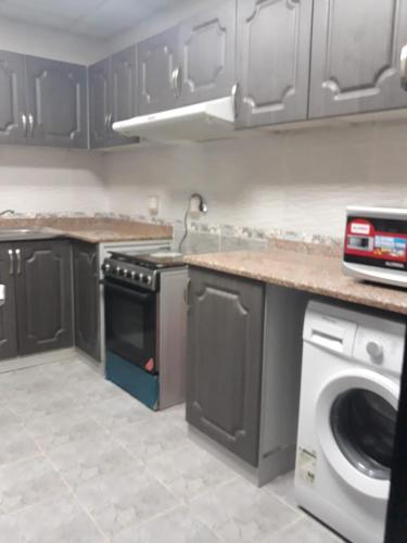 a kitchen with a stove and a washing machine at Affordable Bed Space in Fujairah in Fujairah
