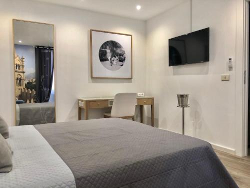 a bedroom with a bed and a desk and a television at SUITE 4 CANTI in Palermo