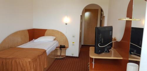 ein Hotelzimmer mit einem Bett und einem TV in der Unterkunft GRAND HOTEL CEAHLAU in Piatra Neamţ