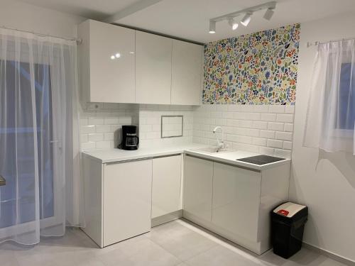 a small kitchen with white cabinets and a sink at Zenit Apartman in Bükfürdő