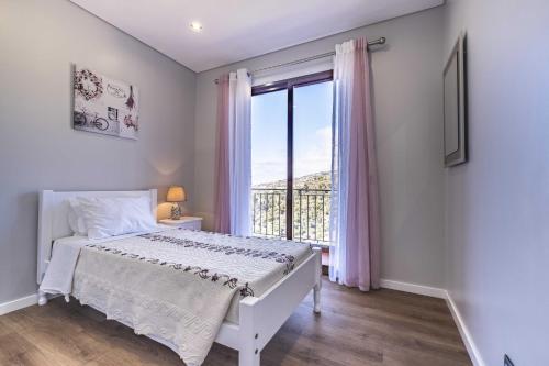 Un dormitorio con una cama y una ventana grande. en Casa do Miradoro, en Santa Cruz
