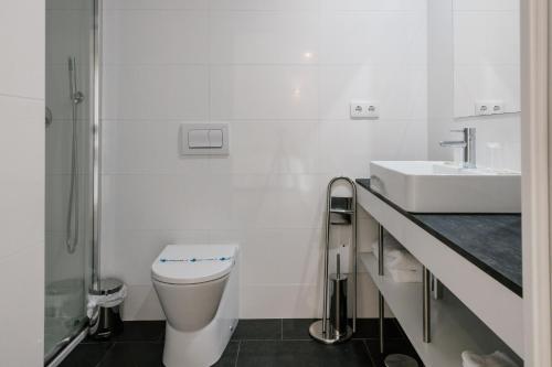 a white bathroom with a toilet and a sink at Quinta do Eden in Vagos